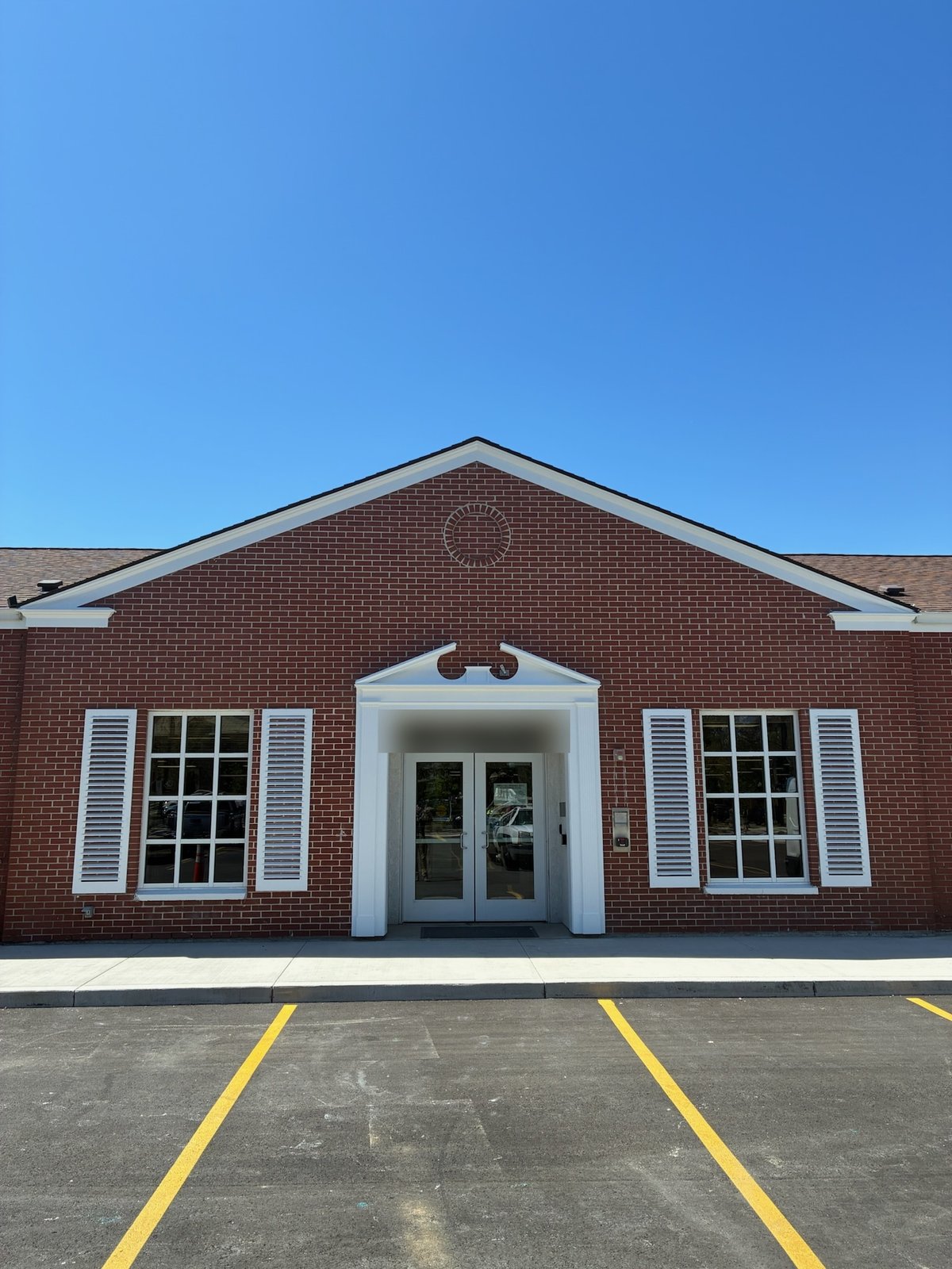Restored brick building entrance in Boise with rebuilt white pillars, pediment moulding, fascia, and louvered shutters