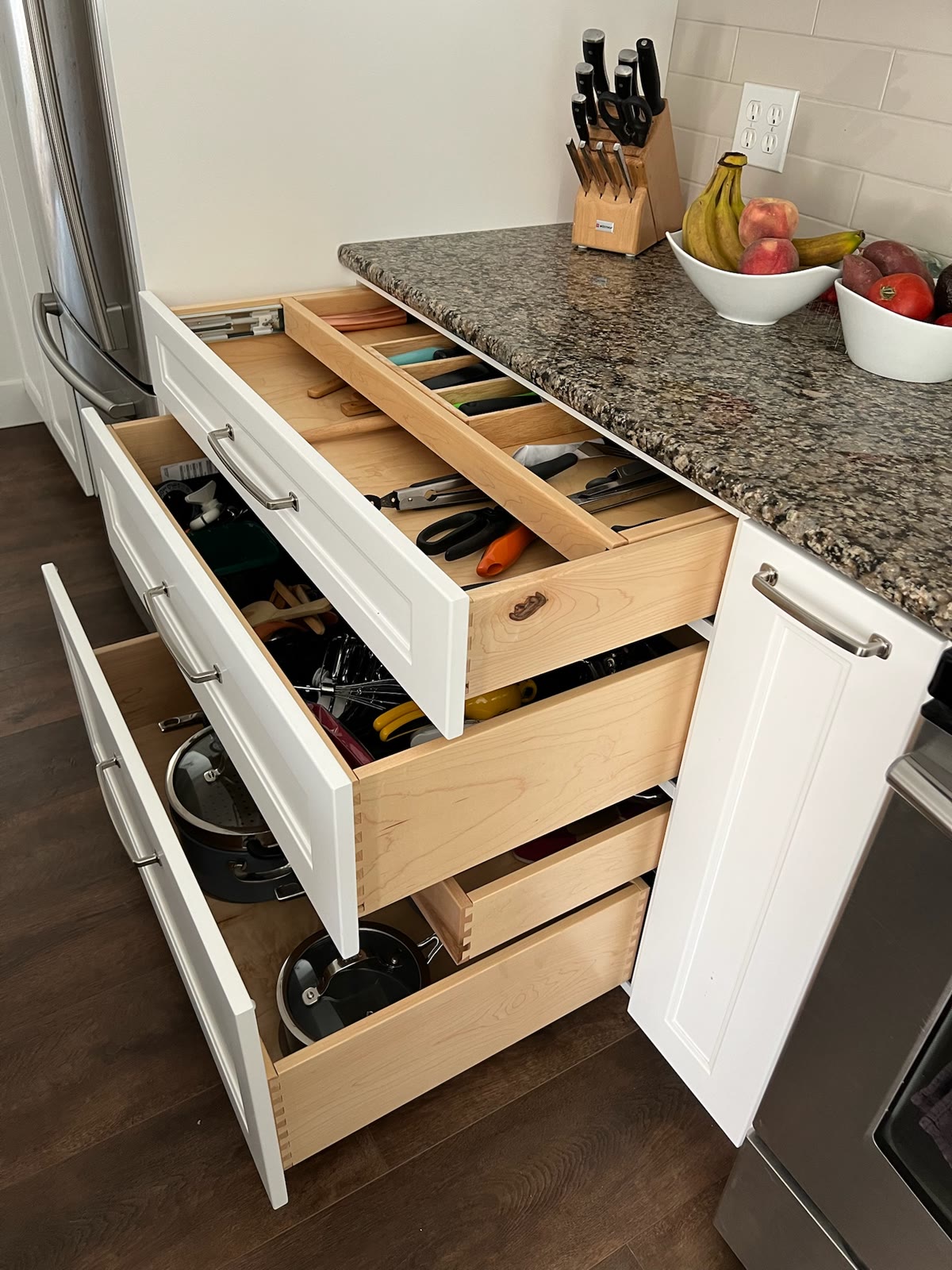Custom kitchen drawer bank with an integrated utensil tray and deep drawers for pots and pans