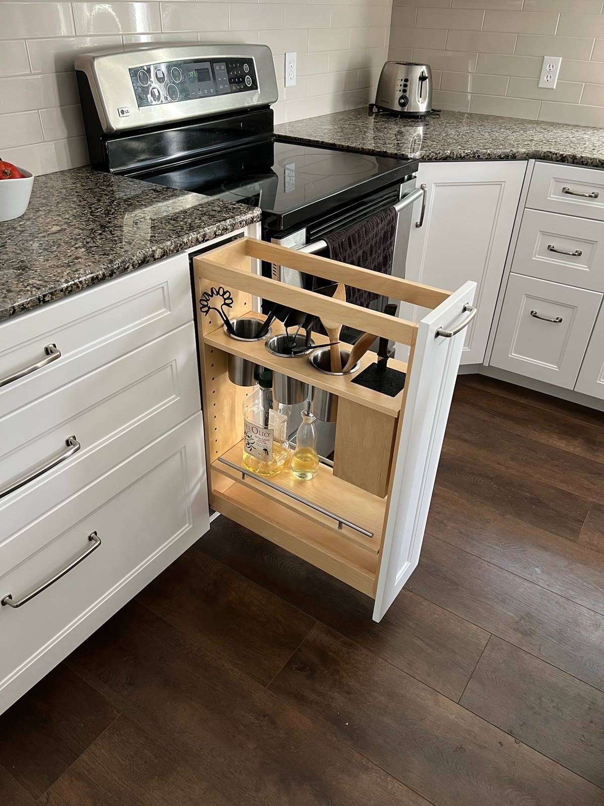 Narrow custom cabinet pullout beside a kitchen range for utensils, oils, and cooking accessories