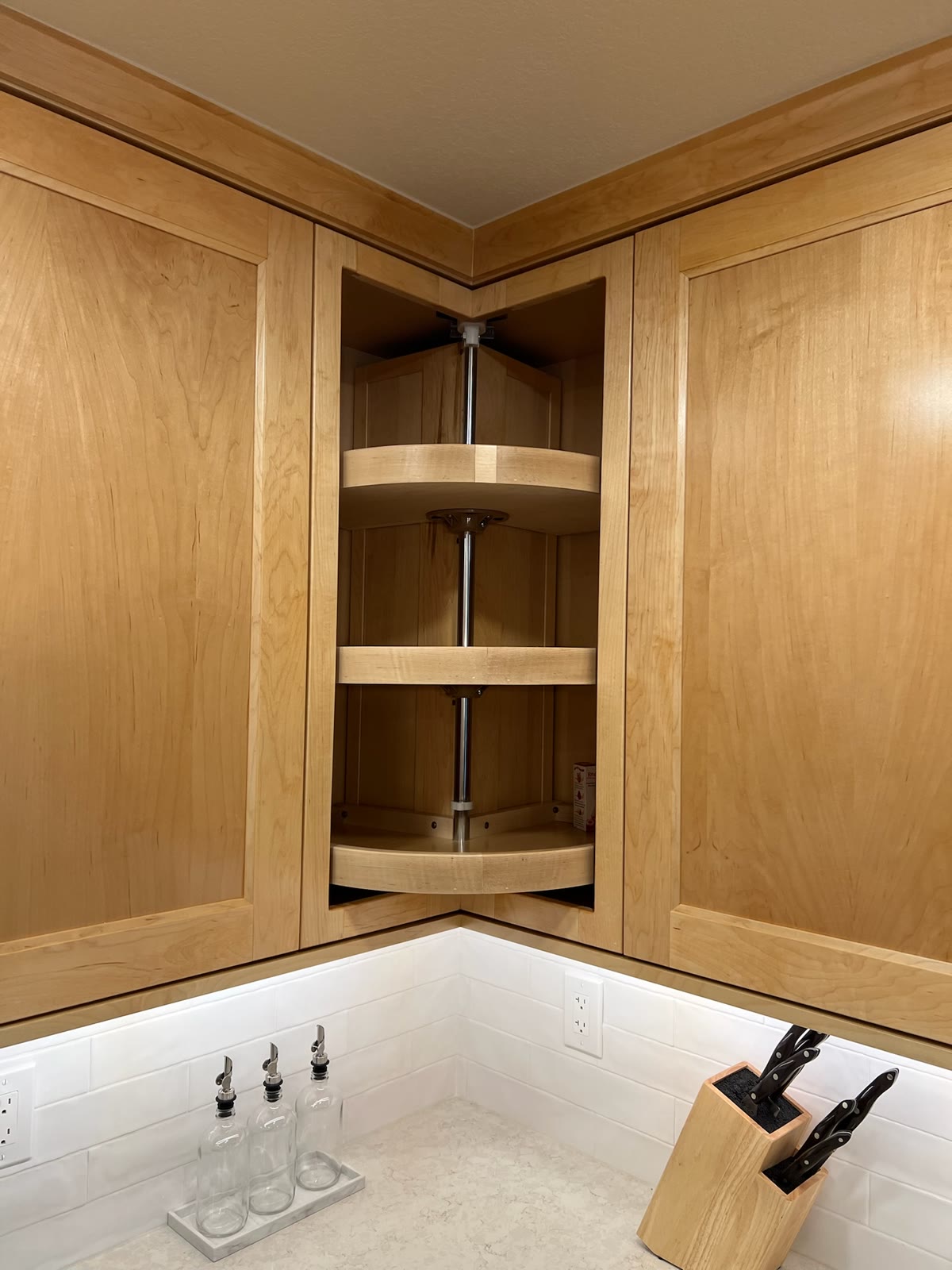Custom natural-wood corner kitchen cabinet with three swing-out storage shelves