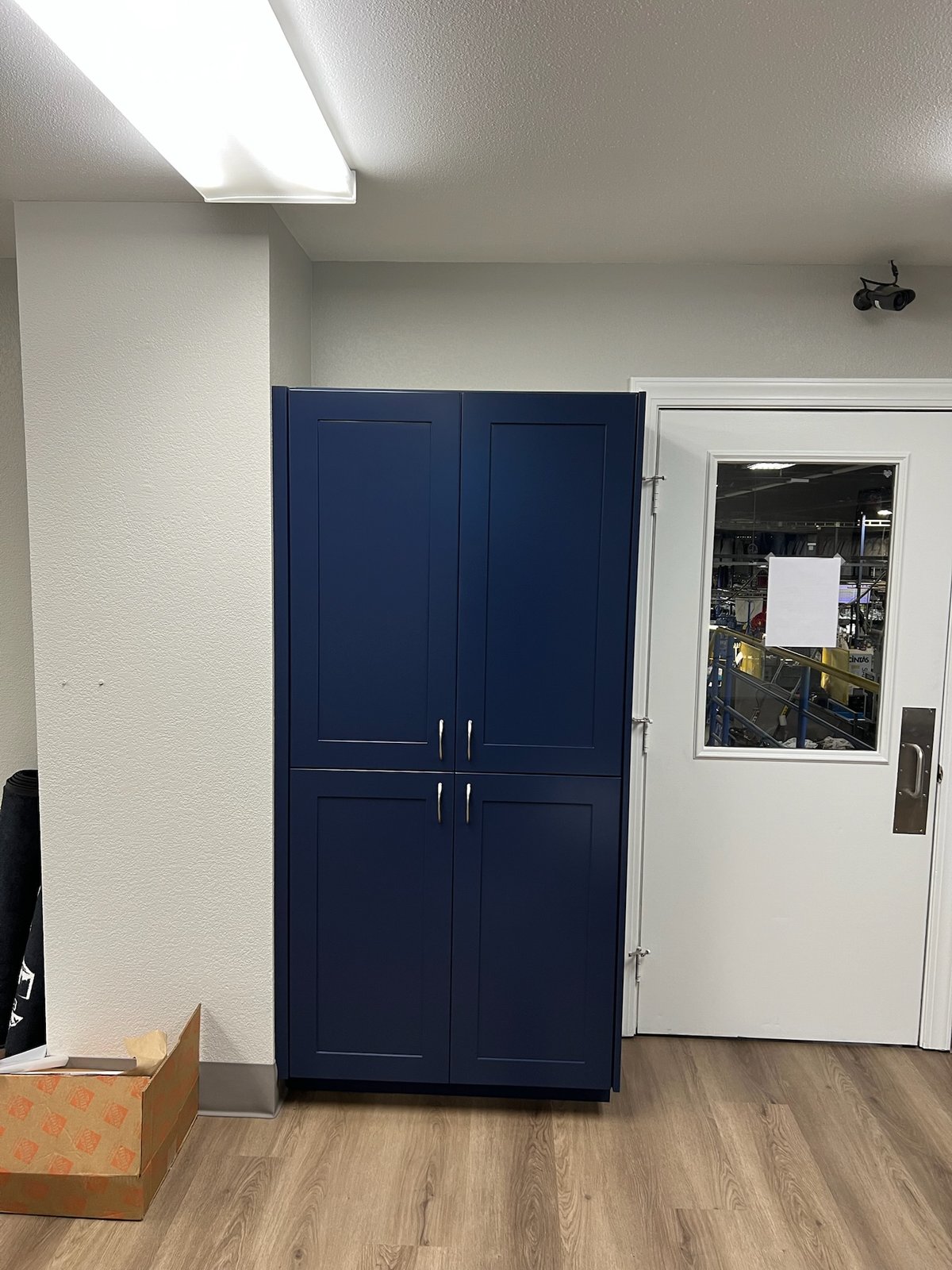 Tall blue commercial storage cabinet beside an existing doorway