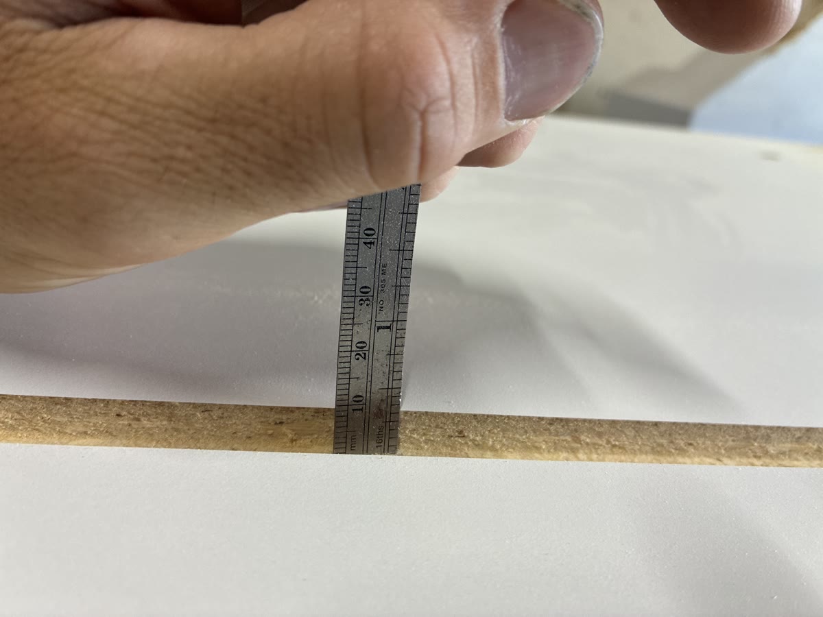 Measuring the thickness of a white-faced wood-composite panel before CNC fabrication